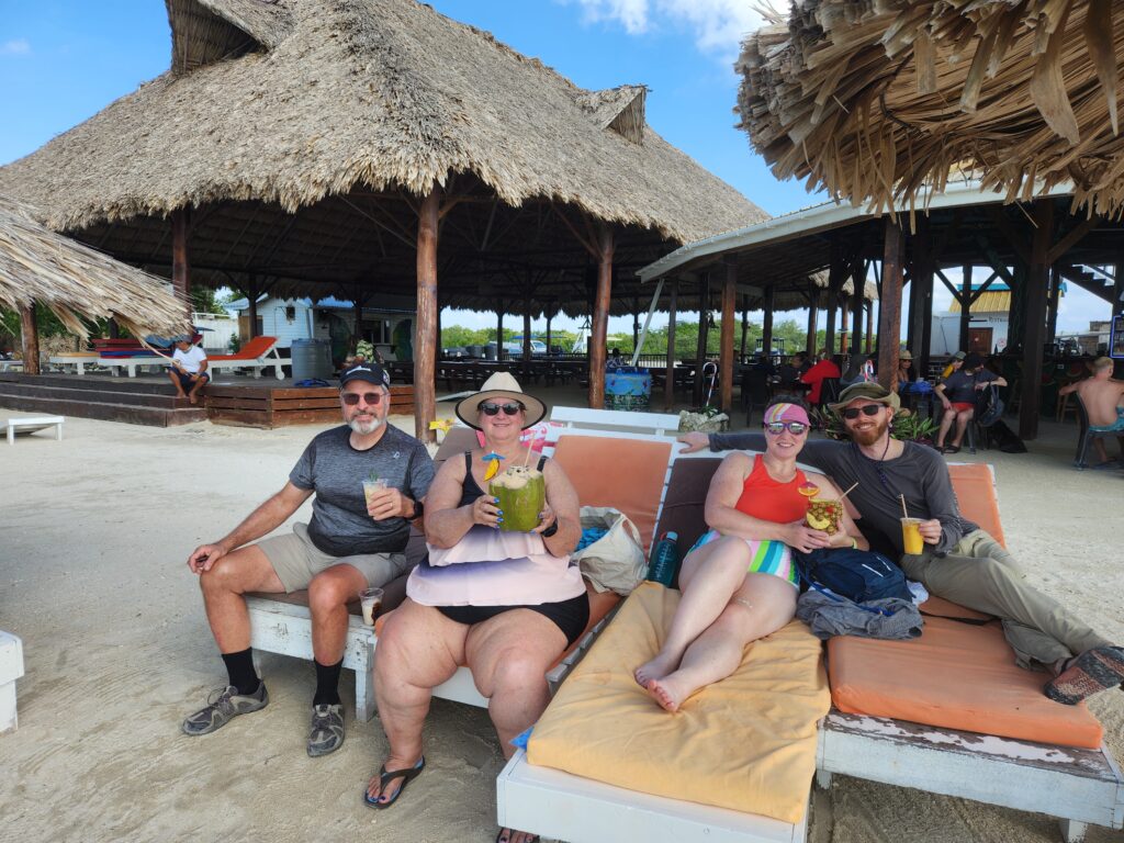 Tom, Linda Amber and Dave reclining on loungers at a tropical beach