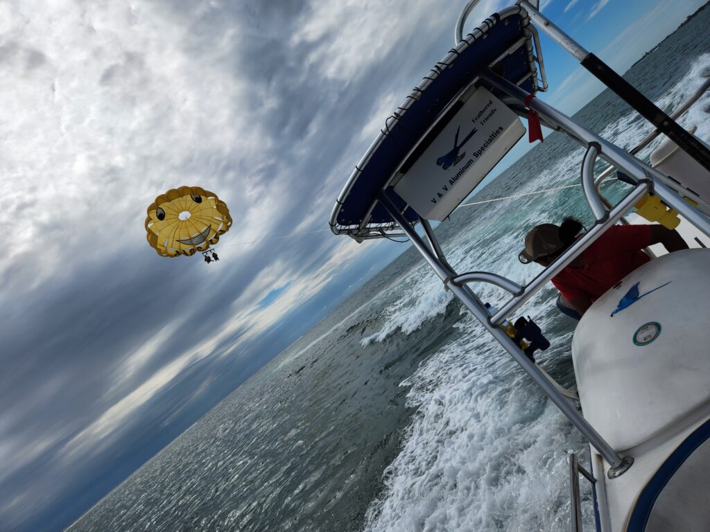 Tom and Amber suspended from a parachute being pulled by a boat